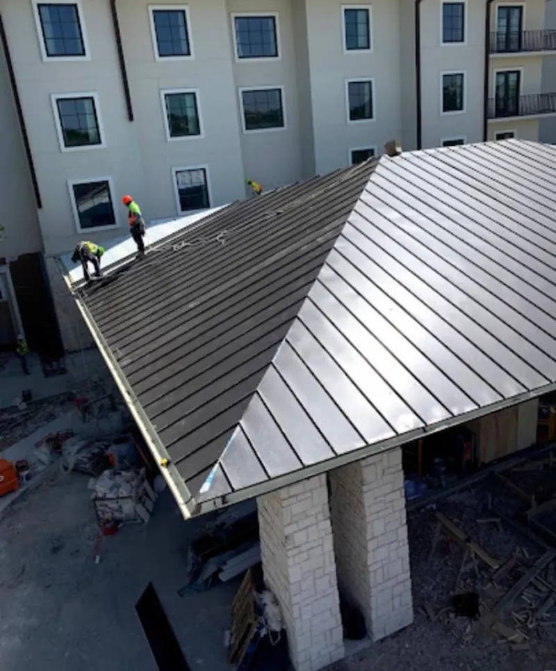 Crew installing standing seam metal roof panels on a commercial project in Pleasant Hill